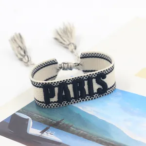 Close-up of woven PARIS embroidery on cream textile friendship bracelet with tassels