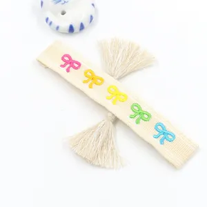 Embroidered friendship bracelet with colorful bows and tassels on a cream base ribbon