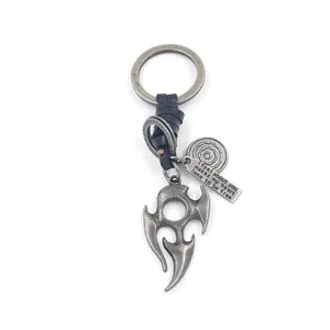Detail of vintage metal flame totem pendant on leather keychain with engraved quote tag