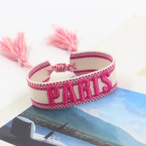 Macro view of woven friendship bracelet with pink Paris embroidery and tassels