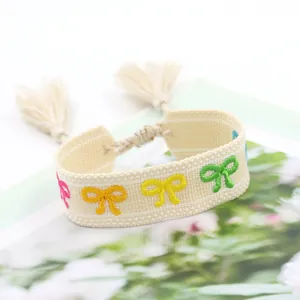 Ethnic woven friendship bracelet with colorful embroidered bows and tassel details