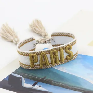 Macro view of woven friendship bracelet with golden PARIS embroidery and tassels