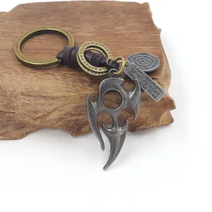 Detail of vintage bronze alloy flame totem pendant and woven leather keychain on wood