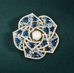 Elegant camellia flower brooch with white pearl and blue crystals on gold base