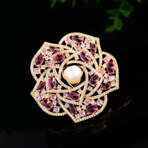 Luxurious camellia flower brooch with pink zircons and center pearl on black background