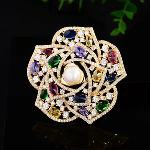 Close-up of golden camellia brooch with colorful gemstones, zircons, and a center pearl