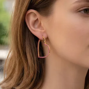 Elegant gold-plated heart-shaped hoop earring with pavé red crystals worn by a model