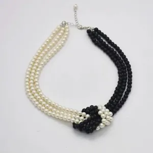 Three-layer knotted faux pearl necklace in black and white contrast with metal clasp