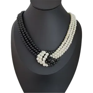 Three-layer knotted faux pearl choker necklace in black and white on a neck display
