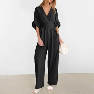 Detail of elegant black deep V-neck jumpsuit with puff sleeves and wide pleated waistband