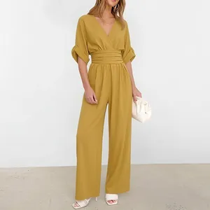 Detail of mustard yellow high-waisted wide leg jumpsuit with V-neck and pleated waist