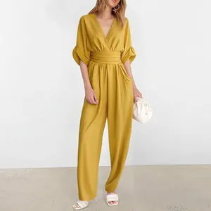 Detail of ginger yellow V-neck jumpsuit featuring ruched waist and wide leg pants