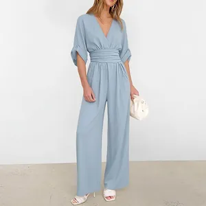 Detail of light blue off-shoulder jumpsuit featuring V-neck and pleated high waist design