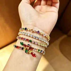 Gros plan de bracelets en pierres colorées avec montures dorées portés par un modèle