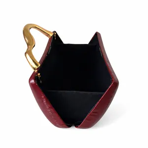 Detailed macro view of an open wine red textured leather handbag with gold wavy handle