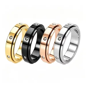 Detail of four spinner rings in gold, black, rose gold, and silver with inlaid crystals