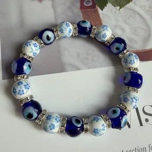 Detailed macro view of blue evil eye beaded bracelet with white floral ceramic accents