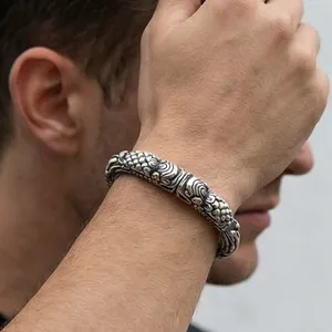 Macro detail of men's vintage silver cuff with intricate cloud and dragon scale patterns