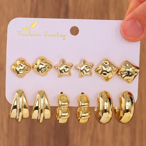 Detail view of 6 pairs of chunky gold C-shaped earrings and studs on a jewelry card