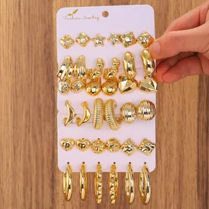 Detailed view of large gold-tone C-shape earrings and textured hoops set on a card