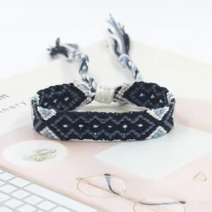 Macro view of woven friendship bracelet with blue geometric patterns and tassel ties