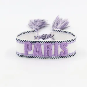 Detailed macro of woven friendship bracelet with purple PARIS embroidery and tassels