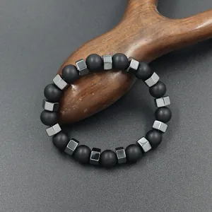 Elastisches Perlenarmband mit matten schwarzen Perlen und grauem Hämatit auf Holz