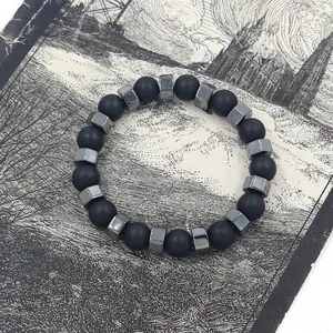 Makro-Detail der mattschwarzen Perlen und quadratischen Metallperlen am Armband