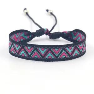 Détail d'un bracelet ethnique tissé avec motifs géométriques roses et perles ajustables