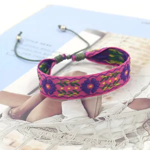 Close-up of pink boho embroidered bracelet with floral patterns and adjustable cord