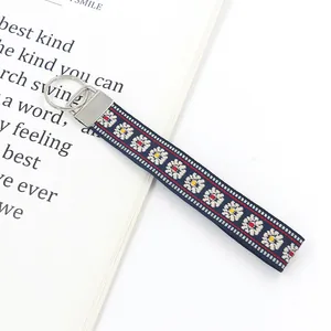 Detail of blue ethnic embroidered wristlet lanyard with white and yellow daisy floral pattern
