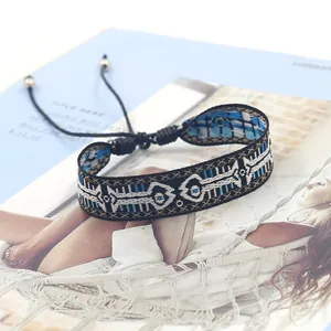 Detail of woven bohemian bracelet with blue geometric patterns and adjustable golden beads