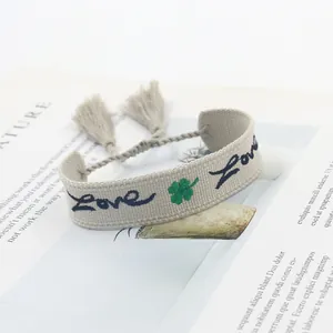 Dettaglio di un braccialetto in stile boho con ricamo Love, quadrifoglio e nappe