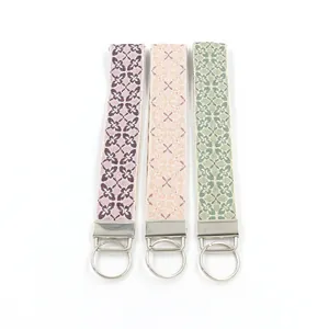 Detailed view of three woven wristlet keychains with floral geometric embroidery patterns