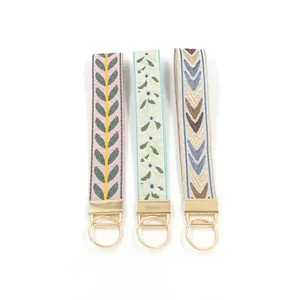 Close-up of three embroidered floral wristlet keychains with gold metal hardware details