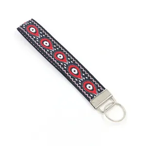 Détail d'un porte-clés poignet brodé style ethnique avec motif géométrique œil rouge