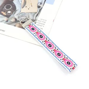 Broderie détaillée d'un œil porte-bonheur sur sangle blanche et porte-clés argenté