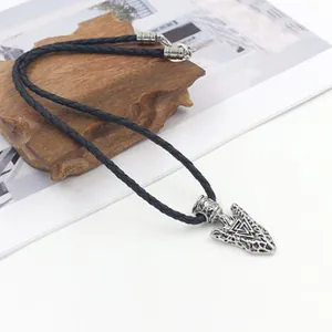 Détail du pendentif Valknut viking en pointe de flèche avec cordon en cuir sur socle bois