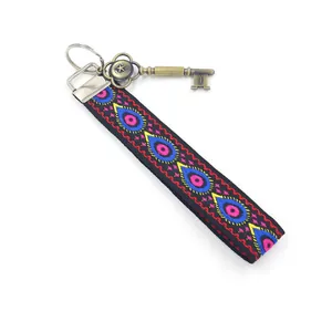 Porte-clés ethnique brodé avec motif paon et breloque clé en bronze vintage sur fond blanc