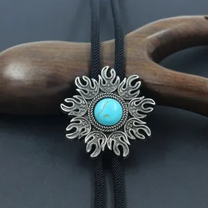 Vintage silver bolo tie with turquoise stone and sunburst pattern on black woven cord