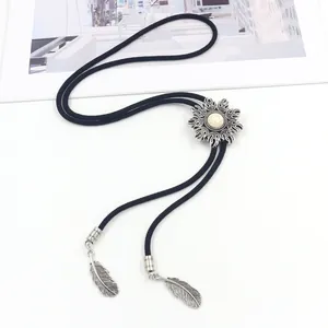 Detail of silver bolo tie slide featuring a sunflower motif and turquoise stone inlay