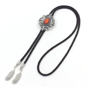 Detail van een vintage bolo-tie met rode edelsteen en zilveren veren metalen tips