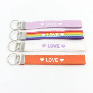 Detalle de cuatro llaveros de tela coloridos con bordado LOVE y cierres metálicos plateados