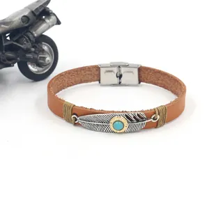 Detailed macro of vintage brown leather bracelet with turquoise feather metal charm