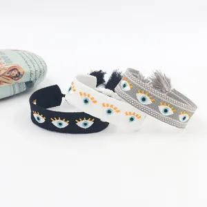 Detail of embroidered bohemian evil eye fabric bracelets with colorful fringe tassels