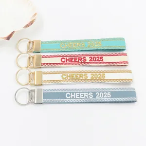 Dettaglio di quattro portachiavi in jacquard con ricamo Cheers 2025 e anelli in metallo