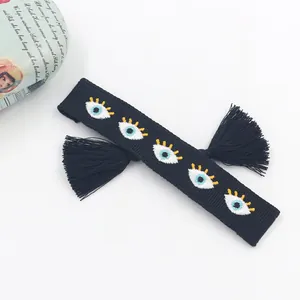 Detailed view of bohemian black woven bracelet featuring five embroidered evil eye patterns