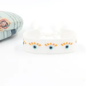 Close-up of white woven evil eye bracelet with embroidery and adjustable tassels