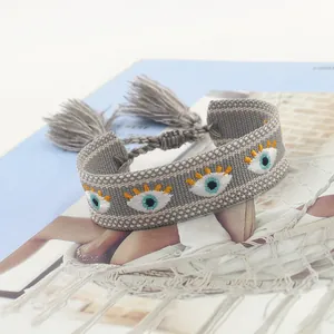 Ethnic woven grey bracelet with blue evil eye embroidery and stylish tassel detail