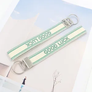 Detail von Good Luck besticktem Canvas-Armband mit silbernem Metall-Schlüsselring